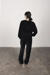 Pantalón de terciopelo negro, corte medio, cintura elástica, bolsillos laterales, logo bordado y costuras delanteras.