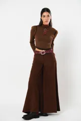Pantalón de corte ancho y tiro alto, confeccionado en pana color marrón chocolate. Presenta un diseño de pierna amplia y fluida, con cierre frontal y trabillas para cinturón.