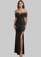 Vestido largo de fiesta color negro con corset estructurado y escote off-shoulder. Presenta detalles de encaje y bordados brillantes en el cuerpo, y una falda larga con tajo lateral profundo.