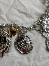 Collar plateado con cadena de eslabones y dijes colgantes con detalles dorados.