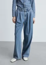 Pantalón de jean estilo wide leg con tiro medio, detalle de pinzas en la cintura, cierre frontal con cremallera y botón, y bolsillos laterales.