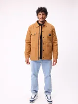 Sobrecamisa de algodón color marrón, con cierre frontal de cremallera y botones a presión. Presenta cuello clásico, dos bolsillos frontales con solapa y cierre de botón, y forro interior de poliéster.