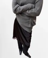 Jersey gris de punto con cuello vuelto, diseño oversize de manga larga y silueta asimétrica.