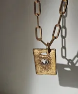 Collar de plata 950 con cadena de eslabones tipo clip y dije rectangular con diseño astrológico grabado y detalles de piedras azules.