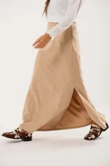 Falda larga color beige confeccionada en tela suave con acabado tipo piel de durazno y cierre invisible lateral.