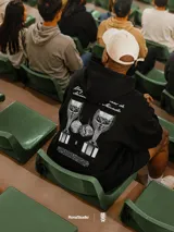 Hoodie negro con capucha y bolsillo frontal tipo canguro. Presenta el escudo de la AUF en el centro del pecho con acabado en relieve y un estampado de alta calidad en la espalda.