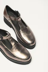 Zapato guillermina color bronce con acabado metalizado, con correa sobre el empeine con hebilla ajustable y suela de goma negra con plataforma.