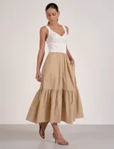 Vestido largo combinado de la marca Elan, con torso en tejido de punto acanalado blanco de escote en V y breteles anchos, y falda midi fluida en color beige con volante fruncido en el ruedo.
