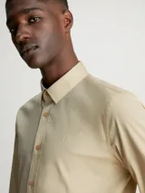 Camisa de vestir color beige, de corte slim, con cuello clásico y cierre frontal con botones.