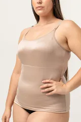 Camiseta modeladora color piel, confeccionada en lycra reforzada con tela de faja en la zona abdominal. Cuenta con breteles regulables y escote redondo.
