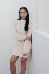 Vestido corto de punto color fucsia, con cuello alto y mangas largas amplias. Diseño holgado y cómodo.