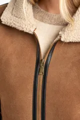 Campera tipo gamulán de corte oversize, confeccionada en material efecto gamuza color camel con interior y detalles de cuello y puños en corderito sintético color crema. Presenta cierre frontal y detalles de ribetes en cuero sintético negro.