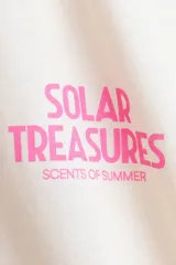 Remera oversized en punto de algodón color beige, de cuello redondo y manga corta, con estampa frontal pequeña en tono rosado con la inscripción "Solar Treasures".