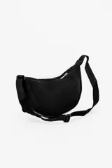 Bandolera color gris claro con forma de media luna, cierre de cremallera y correa ajustable. Incluye etiqueta metálica con el logo de la marca.