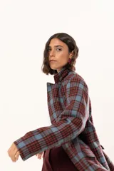 Blazer de corte oversize con estampado de cuadros en tonos azul, bordó y marrón. Presenta solapas clásicas, bolsillos con solapa en el frente y cierre frontal con botones.