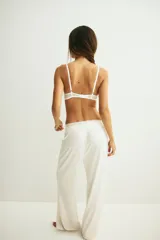 Soutien push-up blanco con aros y copas acolchadas, cubierto de encaje floral. Presenta breteles ajustables y un borde festoneado en la parte superior de las copas.