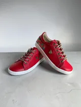 Championes de cuero rojo con detalles pintados a mano en el talón, suela blanca de goma y cordones beige.