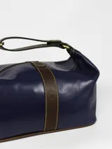 Necessaire de cuero verde con detalles en cuero marrón, cuenta con una manija superior y cierre superior.