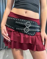 Cinturón ancho de cuero sintético negro con diseño de doble hebilla circular, decorado con múltiples ojalillos metálicos y tachas plateadas en los bordes.