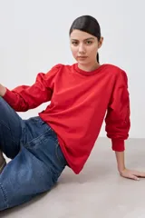 Sweatshirt de algodón color rojo, con cuello redondo y mangas largas abullonadas que presentan detalles de calados bordados. Posee puños elásticos y un diseño holgado.