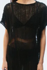 Vestido largo de punto calado color negro, con calce amplio, escote redondo, hombros caídos, mangas cortas y ruedo desflecado.