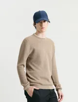Sweater de punto con textura tipo waffle, cuello redondo y mangas largas con puños acanalados.