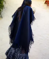 Chal de tejido liviano con terminaciones desflecadas en los bordes, ideal para usar como capa o accesorio versátil.