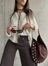 Camisa beige de manga larga, con detalles bordados en el frente y botones decorativos.