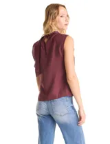 Blusa sin mangas color blanco, confeccionada en crepe con acabado satinado. Presenta un cuello alto decorado con mostacillas y una sobrecapa drapeada en el frente. La espalda cuenta con una abertura tipo gota y cierre de botón.