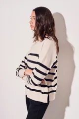 Sweater beige con rayas horizontales negras, de corte holgado y mangas largas.