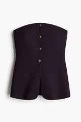 Top strapless de punto roma en color negro, con diseño entallado y cierre frontal de botones dorados, presentando un sutil corte acampanado en el bajo.