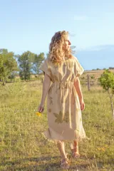 Vestido color beige con estampado de hojas, corte recto, largo midi y ajuste en la cintura con cordón.