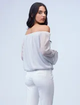 Blusa plateada de gasa lurex con escote off-shoulder, mangas largas abullonadas y terminación anudada en el ruedo.