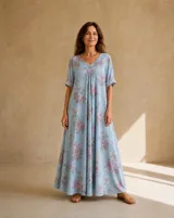 Vestido largo celeste con estampado floral rosado y gris, escote en V y mangas cortas con vuelta.