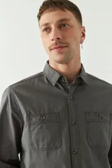 Camisa de gabardina color gris oscuro, con corte slim, manga larga, cuello clásico, cartera abotonada y dos bolsillos frontales con solapa.