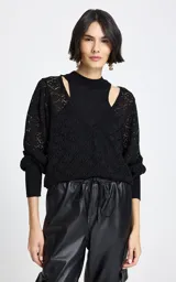 Sweater negro de punto con diseño de doble capa, que combina una base de cuello alto sin mangas con un sobre-sweater de escote en V y mangas largas con calados geométricos.