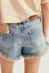 Short de denim azul con diseño de distintos lavados tipo patchwork, talle medio y ruedo deshilachado y desestructurado con roturas.