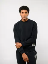 Buzo de felpa color crema, con cuello redondo, manga larga tipo raglán y puños y dobladillo acanalados. Incluye una etiqueta con el logo de Umbro en la parte delantera.