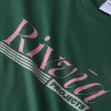 Remera verde con estampa rosa de la marca Rivvia en el frente.