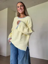 Sweater de punto jersey de algodón color amarillo con silueta oversize, mangas acampanadas y cuello a la base. Presenta terminaciones hechas a mano en crochet a contratono en color celeste con detalles de lurex.