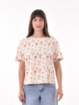 Remera de manga corta color beige con estampado de cactus, palmeras y soles en tonos naranjas.