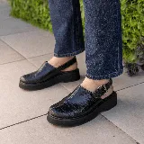 Sueco de cuero vacuno color marrón con estampado de cocodrilo, suela de goma negra y hebilla metálica plateada.