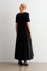 Vestido largo negro oversized con cuello redondo, mangas cortas y detalle fruncido en la cintura con cordón ajustable.