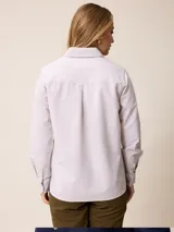 Camisa de manga larga con cuello clásico y cierre frontal de botones, confeccionada en tela de algodón con diseño de rayas verticales finas en color rosado y blanco. Presenta un bolsillo frontal en el pecho con detalle de etiqueta pequeña.