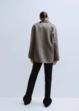 Chaqueta estilo overshirt de paño color gris, con cuello solapa, cierre frontal de botones oscuros, bolsillos con solapa en el pecho y bolsillos aplicados en la parte inferior.