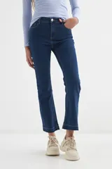 Pantalón de jean azul oscuro, de corte cropped y acampanado, con ruedo desflecado.