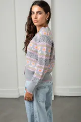 Cárdigan tejido de punto en color gris, con diseño estampado de flores y guardas caladas. Presenta escote en V, cierre frontal con botones y terminaciones acanaladas en puños y ruedo.