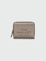 Billetera compacta de cuero color marrón, de diseño plegable con cierre de cremallera perimetral y broche a presión. Interior con múltiples ranuras para tarjetas y compartimento para billetes, con el logo de la marca grabado en bajo relieve.