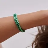 Pulsera rígida de color verde metálico con diseño trenzado.