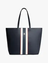 Cartera tipo tote de Tommy Hilfiger en color azul marino, con diseño de franjas verticales en el centro en tonos blanco, azul y rojo. Presenta logo metalizado dorado en la parte frontal y doble asa superior.